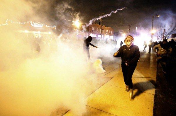 Protesters run from a cloud of tear gas after a grand jury returned no indictment in the shooting of Michael Brown in Ferguson, Missouri
