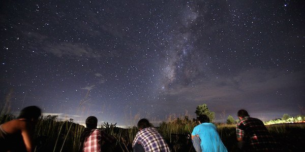 This long-exposure photograph taken on August 12, 2013 shows people watching for the Perseid meteor shower in the night sky near Yangon. The meteor shower occurs every year in August when the Earth passes through the debris and dust of the Swift-Tuttle comet.   AFP PHOTO / Ye Aung Thu        (Photo credit should read Ye Aung Thu/AFP/Getty Images)